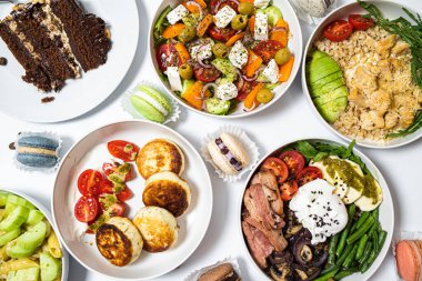 Beyaz arka plandaki et, sebze ve tatlılardan oluşan şenlikli yemekler. Menü ayarlandı.