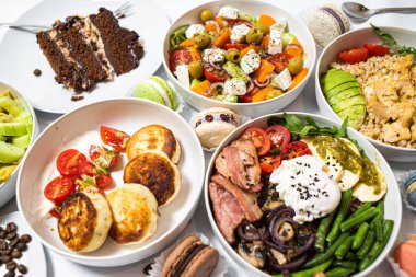 Beyaz arka plandaki et, sebze ve tatlılardan oluşan şenlikli yemekler. Menü ayarlandı.