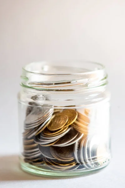 Clear glass jar for tips with coins money isolated on white. Finance concept