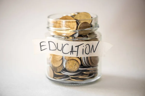 Coins in glass jar with education label. Financial concept.