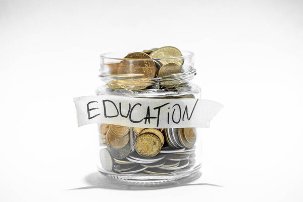Монеты в стеклянной банке с этикеткой образования. Финансовая концепция.