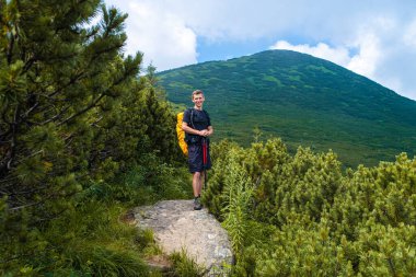 Genç adam dağlarda yürüyüş yapıyor.