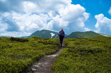 Sırt çantalı bir yürüyüşçü dağlarda yürüyüş yapıyor.