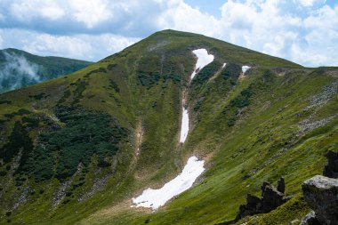 Yeşil çimenleri ve mavi gökyüzü olan güzel dağ manzarası