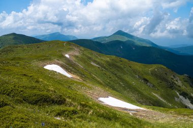 Yeşil çimenleri ve mavi gökyüzü olan güzel dağ manzarası