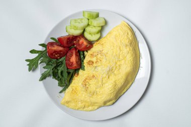 Kızarmış patates, sebzeli ve peynirli beyaz tabakta.