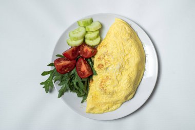 Kızarmış yumurta, sebzeli ve peynirli beyaz tabak.