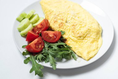 Kızarmış yumurta, sebzeli ve peynirli beyaz tabak.