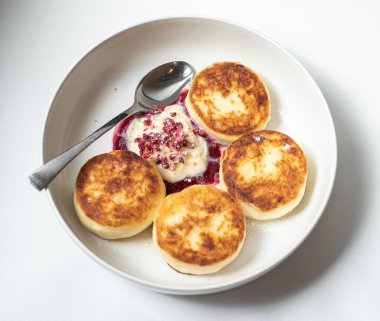 Ekşi kremalı ve peynirli krepler beyaz tabakta.