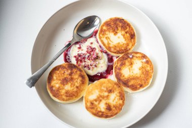 Ekşi kremalı ve peynirli krepler beyaz tabakta.