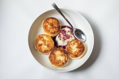 Beyaz tabakta süzme peynirli ve ekşi kremalı krep.