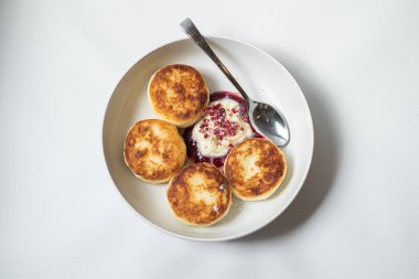 Ekşi kremalı ve peynirli krepler beyaz tabakta.