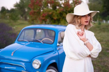 beautiful girl in a white dress and hat in a lavender field at sunset