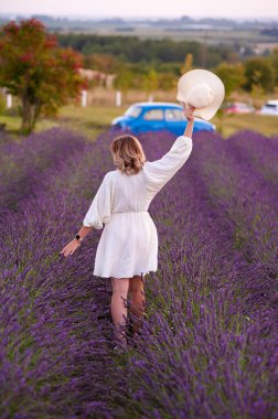 beautiful girl in a white dress and hat in a lavender field at sunset