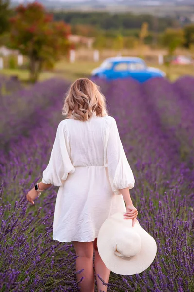 beautiful girl in a white dress and hat in a lavender field at sunset