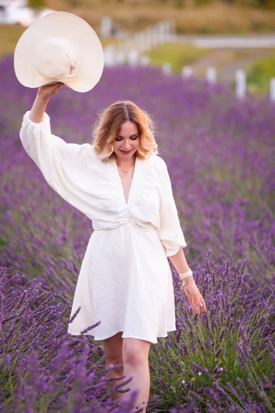 beautiful girl in a white dress and hat in a lavender field at sunset