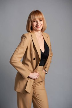 Gri arka planda takım elbiseli güzel bir kadının portresi.