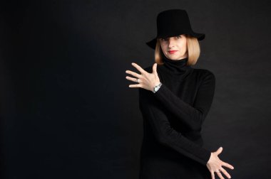 Siyah şapkalı, beyaz gömlekli, siyah arka planda güzel bir kadın.