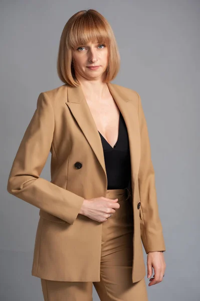 beautiful young woman in a suit and a jacket on a gray background