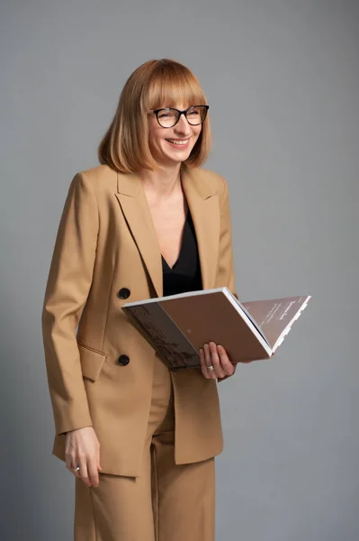 portrait of a beautiful young woman in a suit and glasses with a folder in her hands
