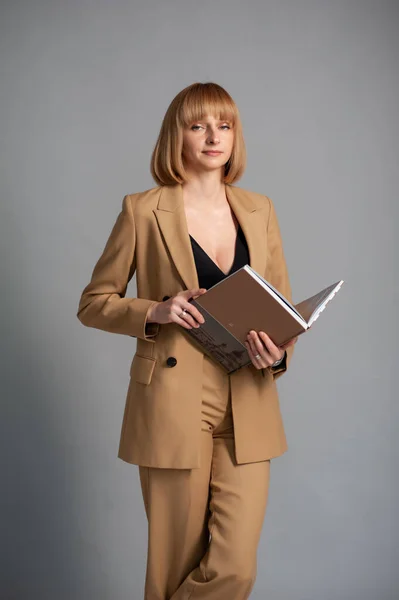 beautiful young woman in a suit and a black jacket and a white shirt on a gray background