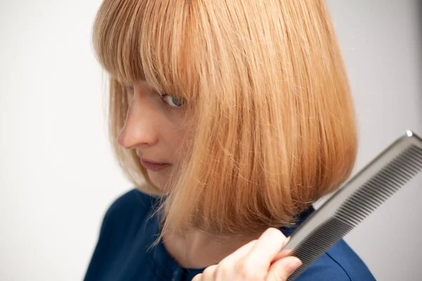 woman combing hair with scissors