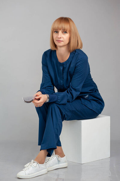 красивая молодая женщина в белой рубашке и синих джинсах сидит на стуле и смотрит в камеру