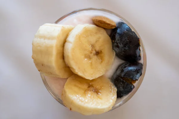 バナナ アーモンド 梅をグラスに入れた乳製品デザートの上からの眺め トップ表示 — ストック写真