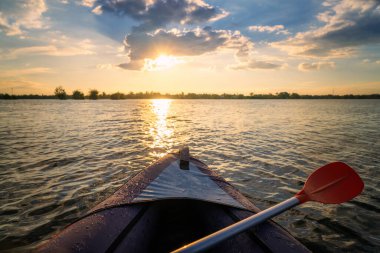 Arka planda günbatımı olan bir kano.