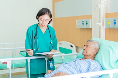 Asyalı hemşire yaşlı Asyalı erkeğe bakıyor ve hastanede onun sağlığı, sağlık ve sağlık hizmetleri konsepti hakkında konuşuyor..