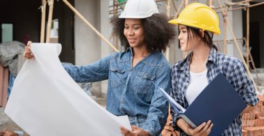 Mühendis ve kadın ustabaşı çeşitli işlevleri kontrol etmek için inşaat alanında duruyorlar..