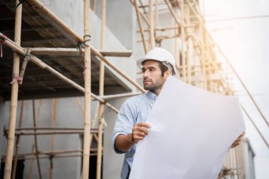 İnşaat alanında duran genç erkek mühendisler çeşitli fonksiyonları kontrol ediyorlar..