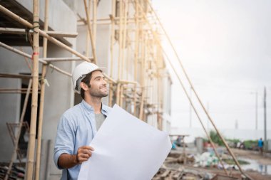 İnşaat alanında duran genç erkek mühendisler çeşitli fonksiyonları kontrol ediyorlar..