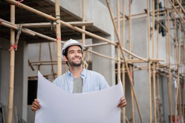 İnşaat alanında duran genç erkek mühendisler çeşitli fonksiyonları kontrol ediyorlar..