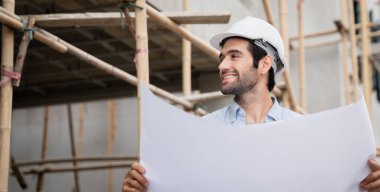 İnşaat alanında duran genç erkek mühendisler çeşitli fonksiyonları kontrol ediyorlar..