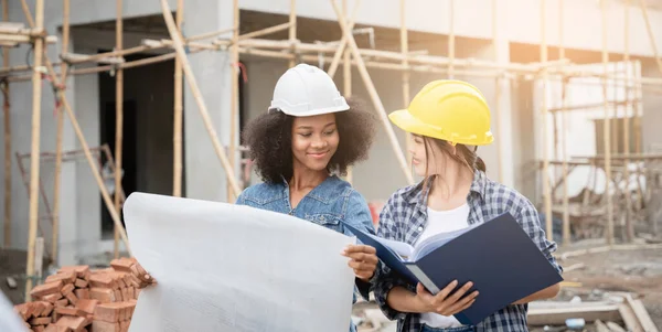Mühendis ve kadın ustabaşı çeşitli işlevleri kontrol etmek için inşaat alanında duruyorlar..