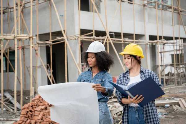 Mühendis ve kadın ustabaşı çeşitli işlevleri kontrol etmek için inşaat alanında duruyorlar..