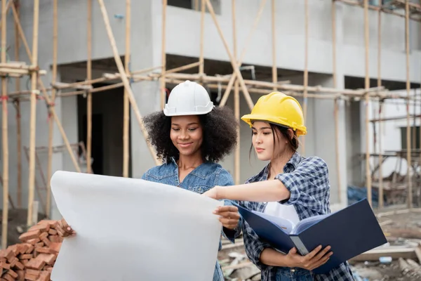 Mühendis ve kadın ustabaşı çeşitli işlevleri kontrol etmek için inşaat alanında duruyorlar..