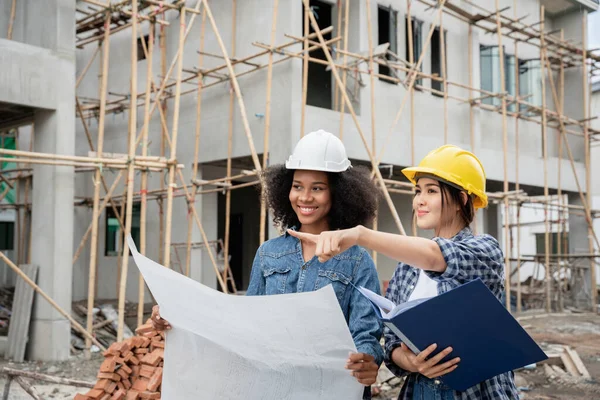 Mühendis ve kadın ustabaşı çeşitli işlevleri kontrol etmek için inşaat alanında duruyorlar..