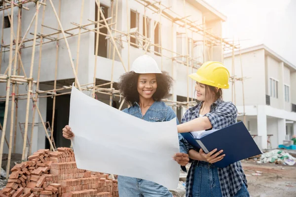 Mühendis ve kadın ustabaşı çeşitli işlevleri kontrol etmek için inşaat alanında duruyorlar..