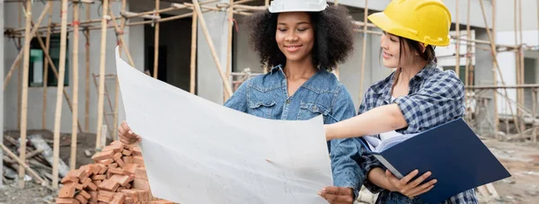 Mühendis ve kadın ustabaşı çeşitli işlevleri kontrol etmek için inşaat alanında duruyorlar..