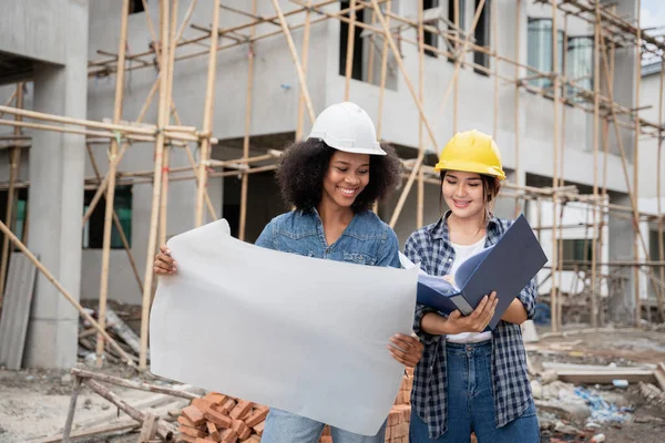Mühendis ve kadın ustabaşı çeşitli işlevleri kontrol etmek için inşaat alanında duruyorlar..