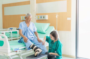 Kadın bir hemşire hastanede diz sorunu olan bir hastanın kafasını muayene eder..