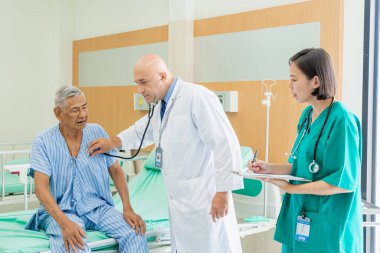 Doktor ve hemşire yaşlı adamı kontrol edip hastanede iyileşme, tıbbi ve sağlık hizmetleri konsepti hakkında konuşuyorlar..