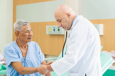 Doktor yaşlı adamı muayene eder ve hastanede iyileşme, sağlık ve sağlık hizmetleri konsepti hakkında konuşur..