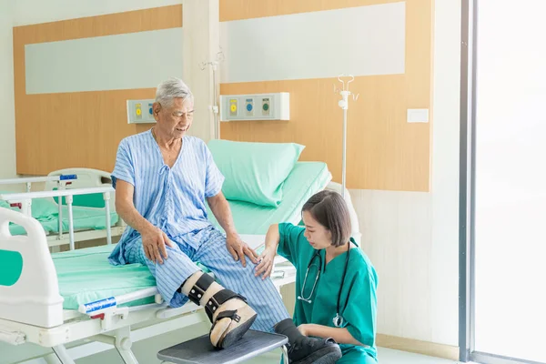 Kadın bir hemşire hastanede diz sorunu olan bir hastanın kafasını muayene eder..