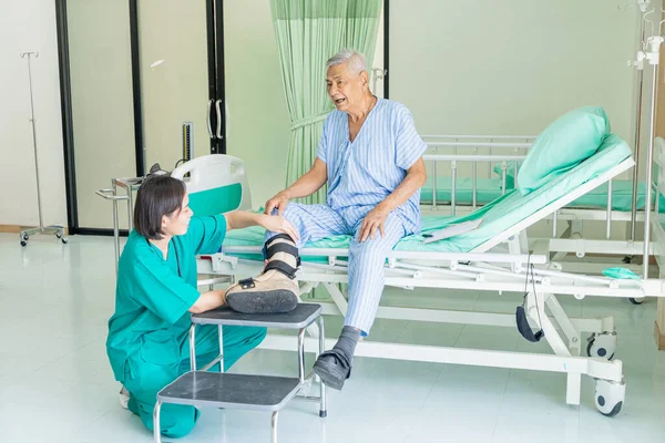 Kadın bir hemşire hastanede diz sorunu olan bir hastanın kafasını muayene eder..