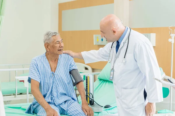 Doktor yaşlı adamı muayene eder ve hastanede iyileşme, sağlık ve sağlık hizmetleri konsepti hakkında konuşur..