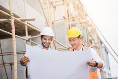 Mühendis ve ustabaşı çeşitli işlevleri kontrol etmek için inşaat alanındaki projeleri tartıştılar..