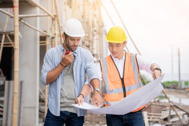 Mühendis ve ustabaşı çeşitli işlevleri kontrol etmek için inşaat alanındaki projeleri tartıştılar..